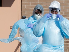 Healthcare workers walk in personal protective equipment.