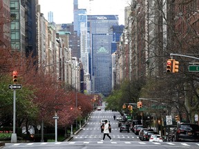 In this file photo a woman walks on an empty Park Avenue on April 10, 2020 in New York City.