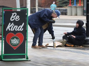 A man stops to make a donation to another on Bank Street March 30.