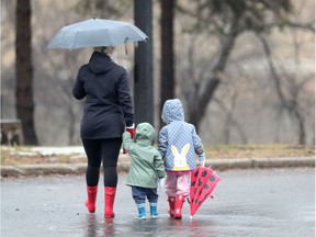 A mother walks her kids in the rain in Ottawa Monday March 30, 2020.