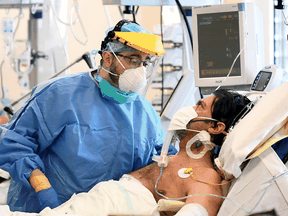 A medical staff member next to a patient suffering from COVID-19 in the intensive care unit at the Circolo hospital in Varese, Italy, April 9, 2020.