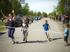 Hester Potts completes her half-marathon run on Sunday, part of a virtual Ottawa Race Weekend. Potts ran the last stretch with sons Euan and Lachlan, while their younger brother Logan helps hold the tape at the finish line.