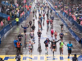Runners come to the finish line of the 122nd Boston Marathon on April 16, 2018, where rain and high winds battered down for the duration. Boston Mayor Marty Walsh has announced that the Boston Marathon will be postponed due to the coronavirus outbreak.