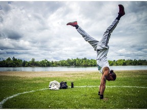 Nick Shea works on his handstands inside a circle painted on the grass at Mooney's Bay Saturday, May 30, 2020.