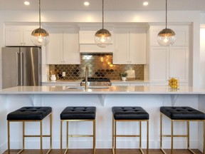 A glossy gold hexagon backsplash brings a memorable pop of colour to the all-white kitchen of Urbandale’s Atlantis II model.