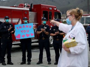 A nurse reacts to a firefighter holding a 'thank you' sign.