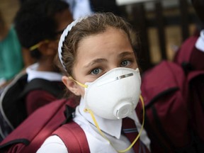 A young girl wears a protective face mask.