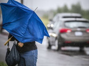 OTTAWA - A woman tries to shelter from the heavy wind and cold rain on Terry Fox Drive in Kanata, Saturday, May 30, 2020. ASHLEY FRASER, Postmedia