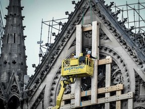 File photo: Workers on a platform are lifted up to a wooden protective structure being secured to the front of the rose window, as the renovation and repair work on Notre-Dame de Paris Cathedral. The cathedral was badly damaged by a huge fire on April 15, 2019.