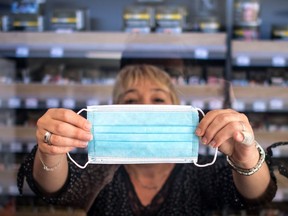 A tobacconist displays a face mask she sells in her shop on May 5, 2020 in Savenay, outside Nantes, on the 50th day of a lockdown in France aimed at curbing the spread of the COVID-19 pandemic, the novel coronavirus. (Photo by Loic VENANCE / AFP)