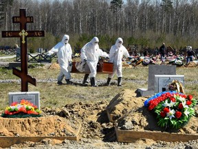 Cemetery workers wearing protective gear bury a coronavirus victim at a cemetery on the outskirts of Saint Petersburg on May 6, 2020.