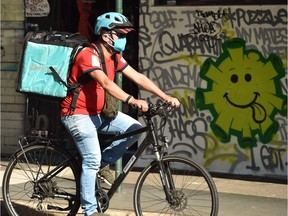 A delivery man cycles past a street art in Sydney on May 8, 2020. - Australia's government unveiled a three-stage plan to get the economy back to a new "COVID-safe" normal by the end of July.