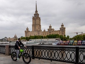 A woman wears a protective face mask as she rides a bike along the Moskva river embankment in central Moscow on May 10, 2020.