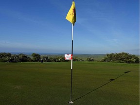 A sign informing members of guidelines is displayed on a flag stick on the first green at The Dyke Golf Club in England on May 13, 2020, as the club reopens as restrictions are eased during the COVID-19 pandemic. Ontario courses can open Saturday.