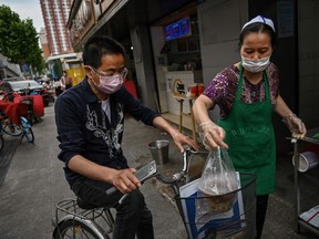 A man wearing a face mask and goggles buys food from a small restaurant in Wuhan in China's central Hubei province on May 13, 2020.