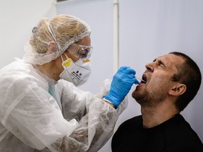 A nurse wearing protective equipment takes a swab sample from a man to be tested for the COVID-19 coronavirus.