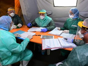 Cuban doctor Jose Enrique Ortiz (centre) and Italian medical staff take part in a daily briefing in a tent formally used for COVID-19, at the patient rehabilitation center inside the field hospital in Crema, southeast of Milan, on May 15, 2020.