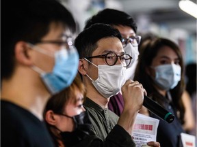 Pro-democracy Demosisto Party member Nathan Law (C) speaks to the press as he and other members of his party including Joshua Wong (L) distribute flyers against China's controversial national security law for Hong Kong, in Hong Kong on May 22, 2020.