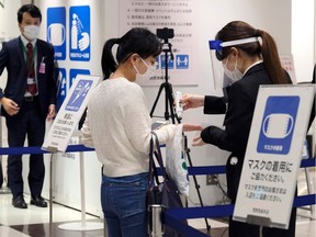 A customer receives a body temperature check when entering Tokyo's Seibu Ikebukuro department store, which resumed business for the first time in 46 days since the emergency declaration, on May 23, 2020.
