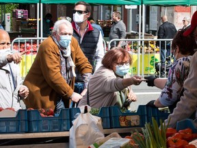 People wearing protective facemasks do their grocery shopping at the open-air market "Marche de la Batte", Belgium's biggest market, in Liege, on May 24, 2020 as Belgium eases lockdown measures taken to curb the spread of the COVID-19.