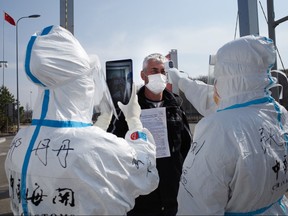 This photo taken on May 1, 2020 shows staff wearing hazmat suits as a precaution against the COVID-19 coronavirus checking the temperature of a driver at a customs checkpoint on the border with Russia at Suifenhe, in China's northeast Heilongjiang province.