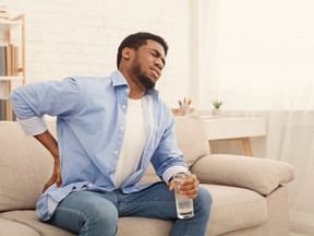 Young black man with back pain at home