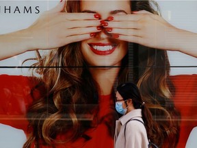 A woman wearing a protective face mask walks by a poster in a Debenhams store in Manchester city centre following the outbreak of the coronavirus disease (COVID-19), Manchester, Britain May 11, 2020.