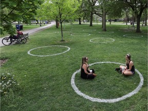 Women sit in a field where circles were painted to help visitors maintain social distancing to slow the spread of the coronavirus disease (COVID-19) at Trinity Bellwoods park in Toronto.