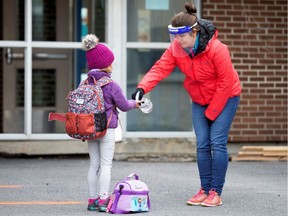 A student has her hands sanitized in the schoolyard.