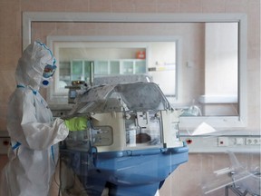 A medical specialist wearing personal protective equipment (PPE) takes care of a newborn baby at the maternity ward of the City Clinical Hospital Number 15 named after O. Filatov, which delivers treatment to patients infected with the coronavirus disease (COVID-19), in Moscow, Russia May 25, 2020.