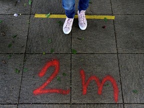 A woman stands on a physical distancing marker.