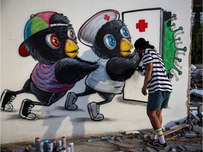 Mue Bon, a Thai street art paints a coronavirus mural depicting characters attempting to keep a virus at bay in Bangkok, amidst an outbreak of the coronavirus disease (COVID-19) in Thailand, May 21, 2020.