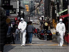 Workers wearing protective suits and masks spray disinfectant in the Itaewon area of Seoul, South Korea, on Monday, May 11, 2020. South Korea is seeing a sudden increase in cases tied to nightclubs in Seoul, raising concerns over a potential second wave of infections.