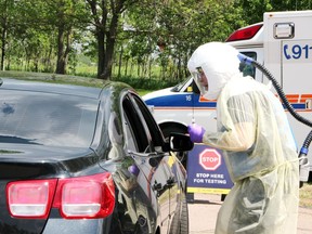 Lee Chantrell, an advanced care paramedic with the County of Renfrew, speaks to the occupants of a vehicle during the a pop-up drive-thru testing clinic for COVID-19 in the parking lot of the Renfrew County District Health Unit Pembroke office.