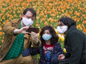 John de Jong, his wife Olivia D'Souza, and their son, Samuel de Jong, stop for a photo with the tulips in Commissioners Park while wearing their face masks earlier this spring. As the economy reopens and more people are out and about, the discussion over face masks becomes even more relevant.