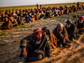 Men suspected of being Islamic State (IS) fighters wait to be searched by members of the Kurdish-led Syrian Democratic Forces (SDF) after leaving the ISIL group's last holdout of Baghouz in 2019.