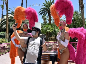 Vlogger Chris Avila records with two showgirls at Flamingo Las Vegas on the Las Vegas Strip after the property opened for the first time since being closed on March 17 because of the coronavirus pandemic, on June 4, 2020 in Las Vegas, Nevada.