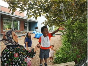 Awand Mageed, left, education assistant, helps Pius play with a bell at the Andrew Fleck Child Care Centre on Queen Mary Street.