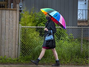 A woman carries a brightly coloured umbrella on a grey afternoon as she walks along Carling Ave.