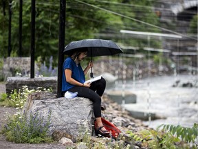 Diana Jung provides her own shelter as she sits along the Ottawa River at the Pumphouse whitewater course on Saturday afternoon.