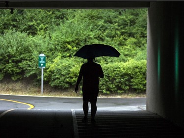 A man walks along the National Capital Commission recreational trail near Mill Street Brewery in the rain on Saturday afternoon.