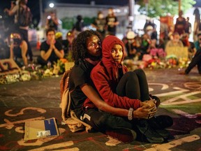 A Somali-American couple, alongside protesters calling for justice for the death of George Floyd, waits after curfew outside the Cup Foods on June 1, 2020 in Minneapolis, Minnesota.