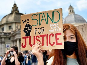 A protester wearing a face mask  holds a placard during a rally in solidarity with the "Black Lives Matter" movement on the Piazza del Popolo in Rome, on Sunday.