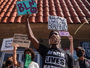TOPSHOT - Protesters hold up placards as they gather on Palmdale Blvd demanding justice for Robert Fuller, a young black man who was found hanging from a tree, on June 16, 2020, in Palmdale, California.