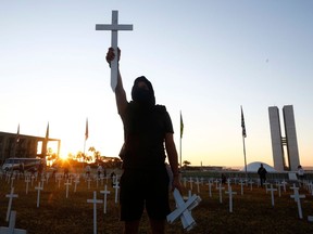 A protester raises a cross during a protest against Brazilian President Jair Bolsonaro and in honour of the people who died of COVID-19.