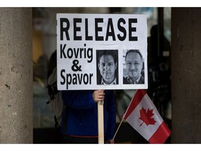 A young man holds a sign bearing photographs of Michael Kovrig and Michael Spavor, who have been detained in China since late 2018.