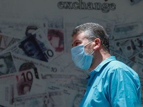 A man wearing a protective face mask walks past a currency exchange shop in central Cairo on Tuesday.