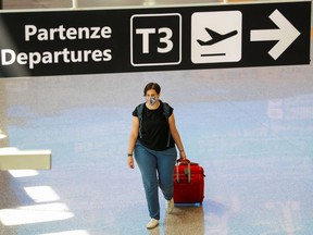 A passenger wearing a protective face mask walks at Fiumicino Airport in Rome on Tuesday, the day EU governments agreed a "safe list" of 14 countries for which they will allow non-essential travel starting in July following the COVID-19 outbreak.