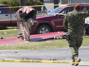 A member of the Canadian Forces walks past the tail section of a Snowbird jet in Kamloops, B.C., on May 18, 2020. A military investigation has found that the ejection seat of one of the military's iconic Snowbirds planes tangled with the pilot's parachute as he tried to escape from the aircraft before it crashed in the U.S. state of Georgia last year. The finding is contained in a report released by the Royal Canadian Air Force today and follows similar concerns about the Snowbirds' ejection seats after Capt. Jennifer Casey was killed during a different crash in British Columbia in May.