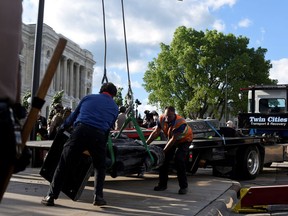 State Patrol officers stand guard as employees of Twin Cities Transport and Recovery work to clear the toppled statue of Christopher Columbus on the Minnesota State Capitol Grounds in St Paul, Minnesota, U.S. June 10, 2020.